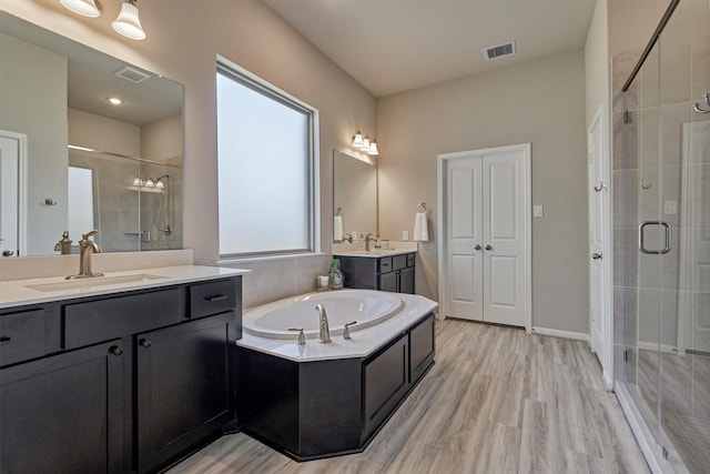 bathroom with plus walk in shower, hardwood / wood-style floors, and vanity