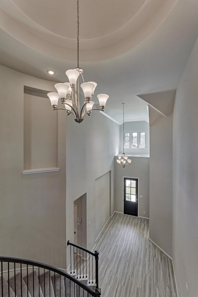 foyer featuring light hardwood / wood-style flooring, a tray ceiling, and a chandelier