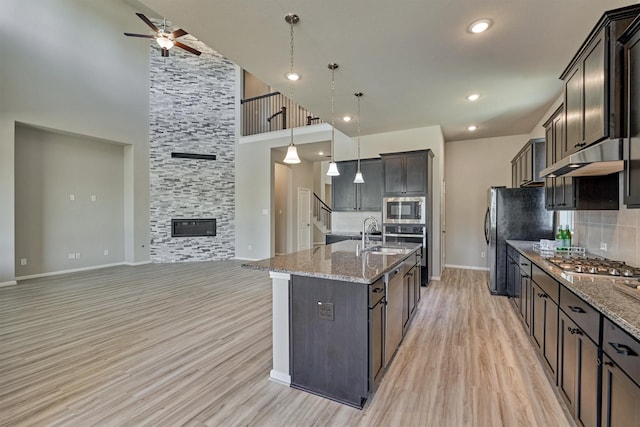 kitchen with stainless steel appliances, dark brown cabinetry, decorative backsplash, and hanging light fixtures