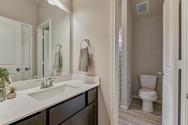 bathroom featuring wood-type flooring, vanity, and toilet