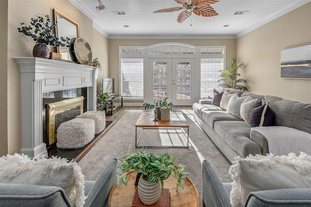 living room featuring a high end fireplace, french doors, ceiling fan, ornamental molding, and wood-type flooring