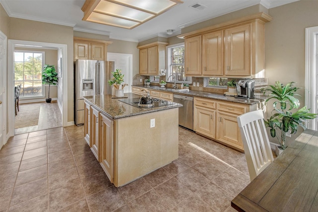 kitchen with a center island, sink, stainless steel appliances, dark stone countertops, and light tile patterned flooring