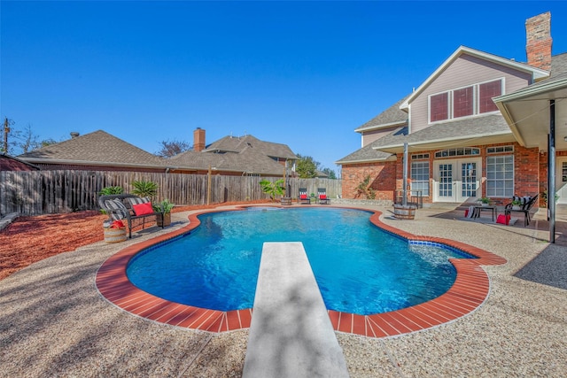 view of pool featuring a patio area, a diving board, and french doors