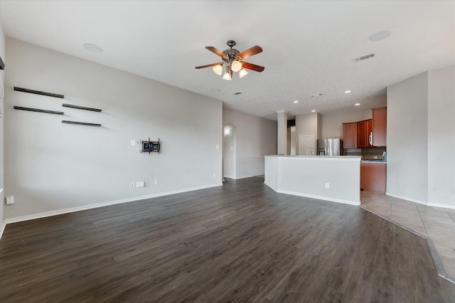 unfurnished living room featuring ceiling fan and dark wood-type flooring