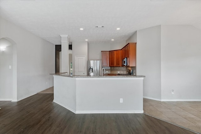 kitchen featuring stone counters, sink, dark wood-type flooring, stainless steel appliances, and tasteful backsplash