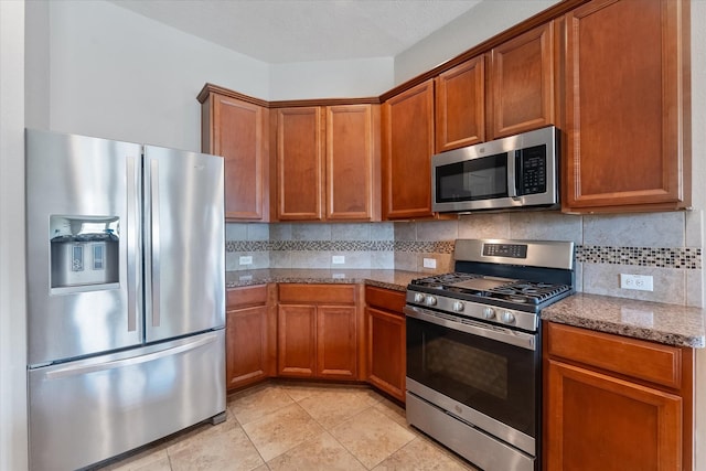 kitchen with backsplash, light stone countertops, a textured ceiling, light tile patterned flooring, and stainless steel appliances