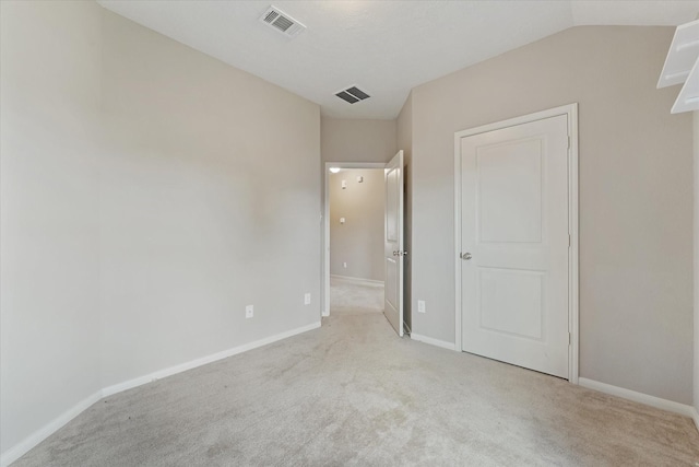 unfurnished bedroom featuring light carpet and lofted ceiling