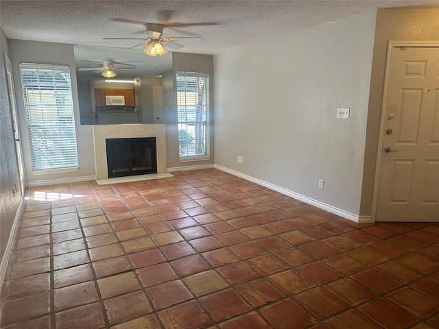 unfurnished living room with tile patterned flooring, a textured ceiling, and ceiling fan