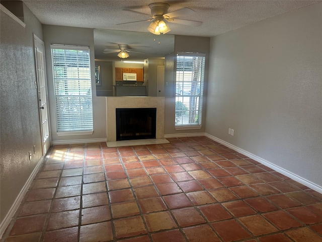 unfurnished living room with tile patterned flooring, plenty of natural light, ceiling fan, and a textured ceiling