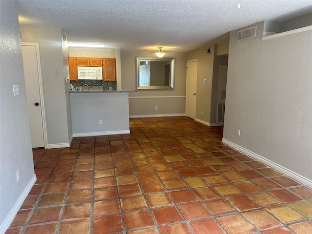 empty room with tile patterned floors, sink, and a textured ceiling