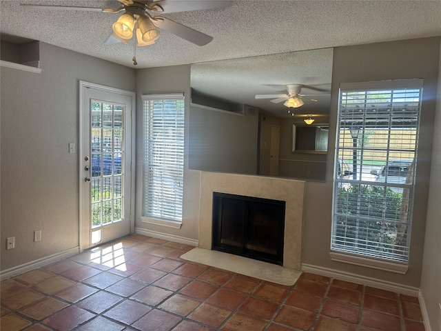 unfurnished living room featuring ceiling fan, tile patterned flooring, and a textured ceiling