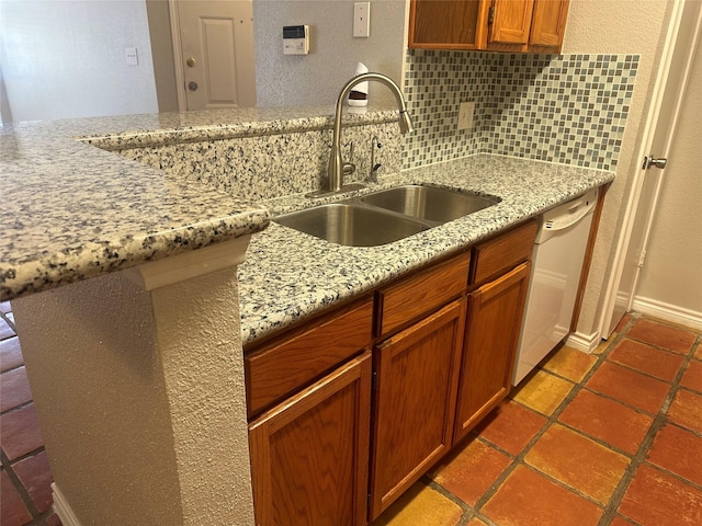 kitchen featuring decorative backsplash, kitchen peninsula, light stone countertops, white dishwasher, and sink