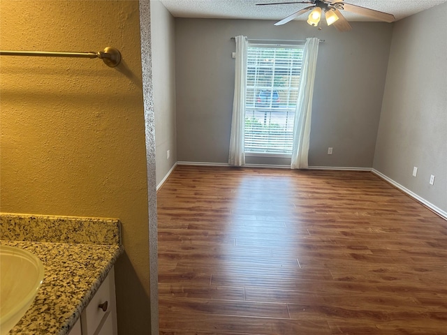 empty room with ceiling fan, hardwood / wood-style floors, a textured ceiling, and sink