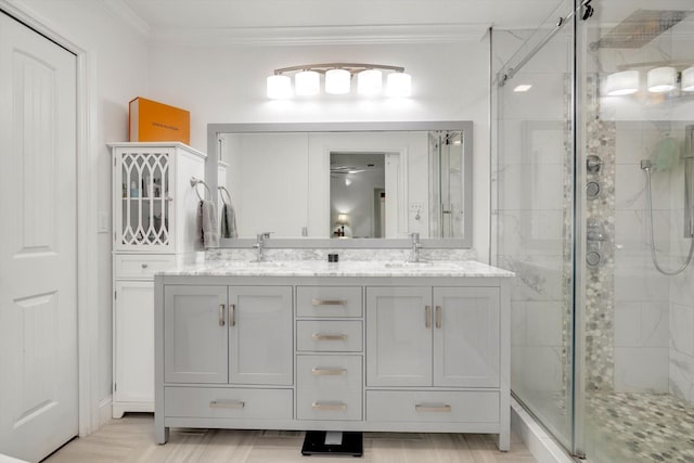 bathroom featuring vanity, a shower with door, and crown molding