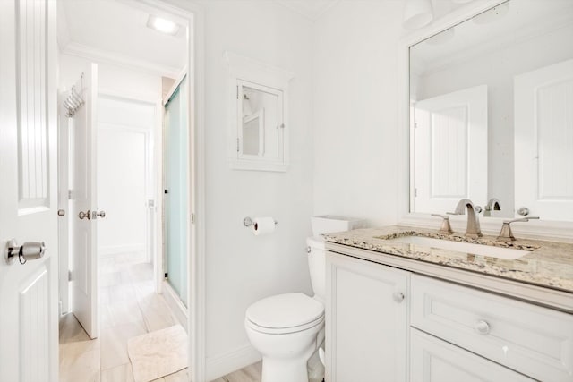 bathroom with crown molding, vanity, a shower with shower door, and toilet