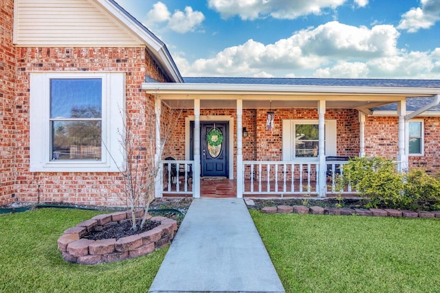 doorway to property with a porch and a lawn