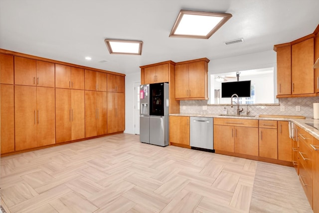 kitchen featuring backsplash, sink, appliances with stainless steel finishes, and light parquet flooring