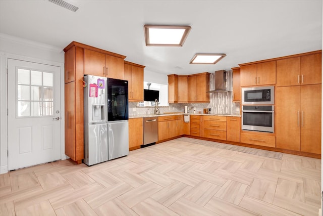 kitchen with wall chimney range hood, backsplash, appliances with stainless steel finishes, and ornamental molding