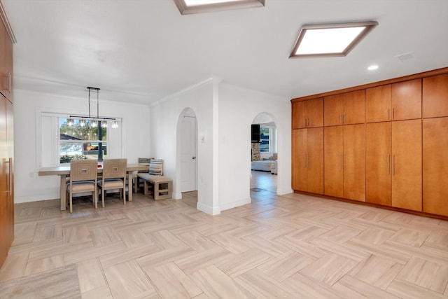 unfurnished dining area featuring a chandelier, light parquet floors, and crown molding