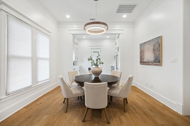 dining room with crown molding and light hardwood / wood-style floors