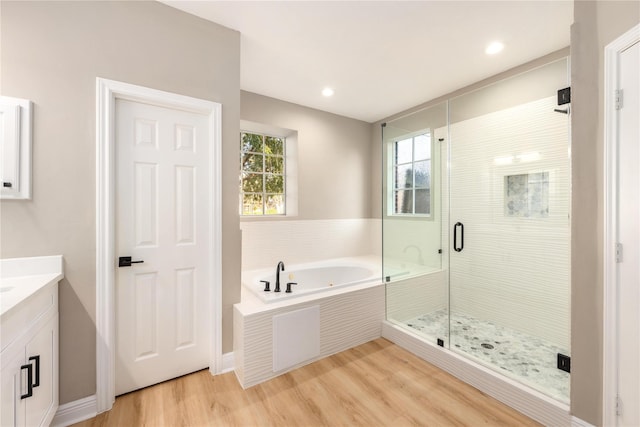 bathroom featuring plus walk in shower, hardwood / wood-style flooring, and vanity