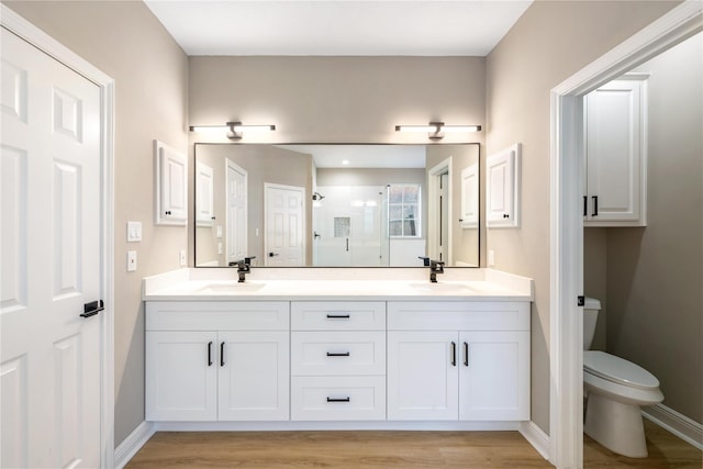 bathroom featuring hardwood / wood-style flooring, toilet, a shower with door, and vanity