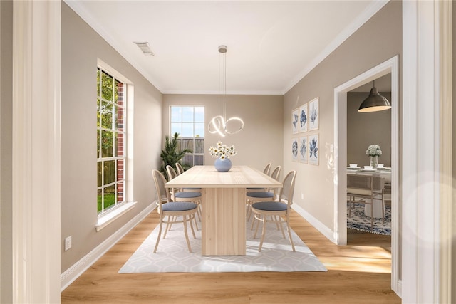 dining room with crown molding and light hardwood / wood-style floors