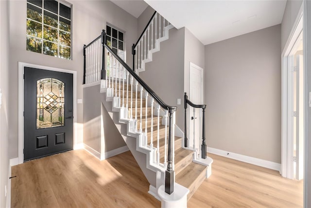 foyer entrance featuring light hardwood / wood-style floors and a towering ceiling