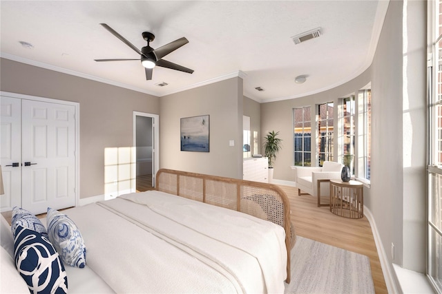 bedroom with ceiling fan, ornamental molding, a closet, and light hardwood / wood-style flooring