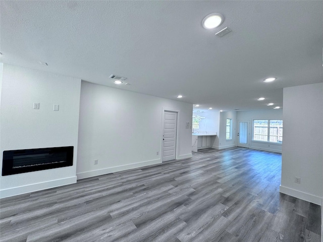 unfurnished living room featuring hardwood / wood-style flooring and a textured ceiling