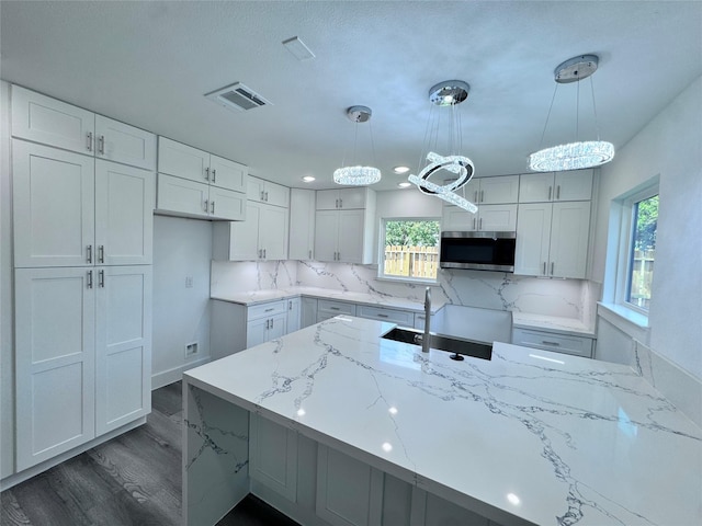 kitchen featuring decorative backsplash, pendant lighting, white cabinetry, and light stone countertops