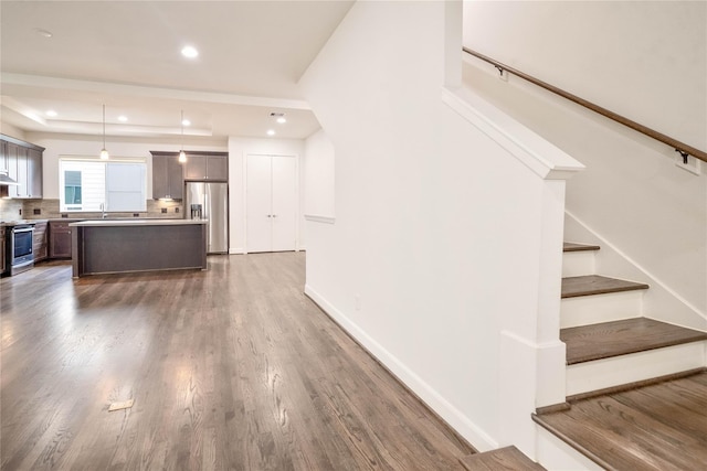 kitchen featuring pendant lighting, a center island, stainless steel appliances, decorative backsplash, and dark hardwood / wood-style flooring