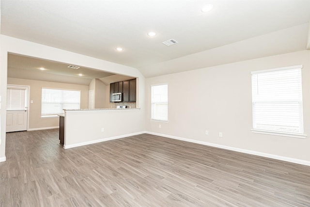 unfurnished living room featuring light hardwood / wood-style flooring, a wealth of natural light, and lofted ceiling