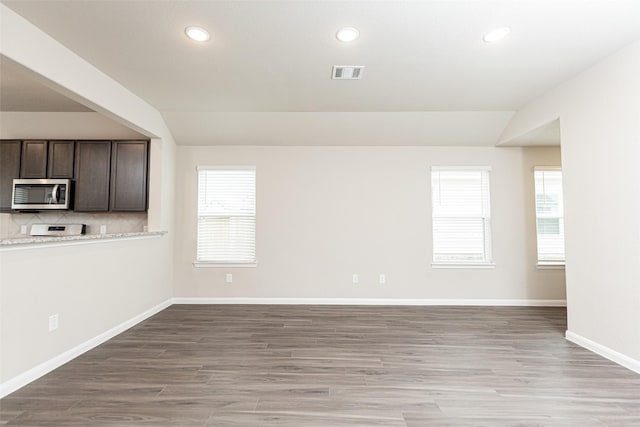 empty room with light hardwood / wood-style floors and vaulted ceiling