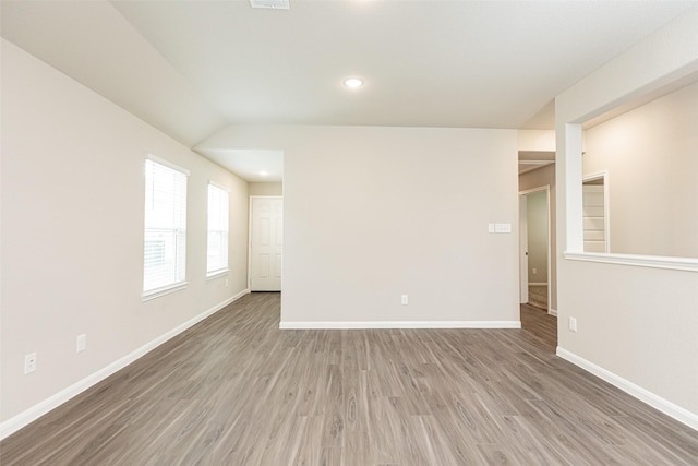 spare room with hardwood / wood-style floors and vaulted ceiling