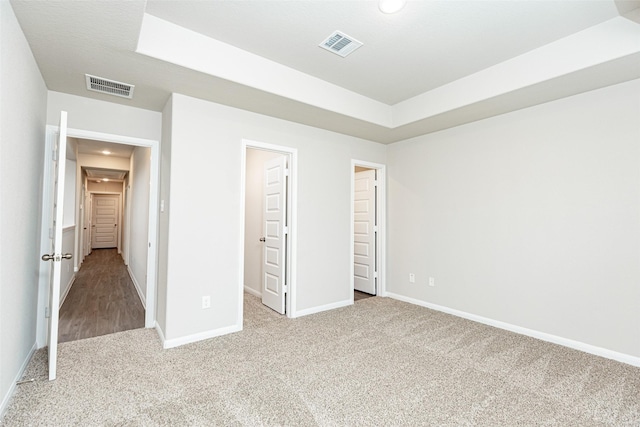 unfurnished bedroom with a raised ceiling and light colored carpet