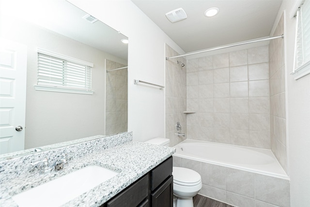 full bathroom featuring hardwood / wood-style floors, vanity, toilet, and tiled shower / bath