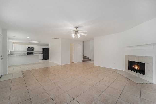 unfurnished living room featuring light tile patterned floors, a fireplace, and ceiling fan