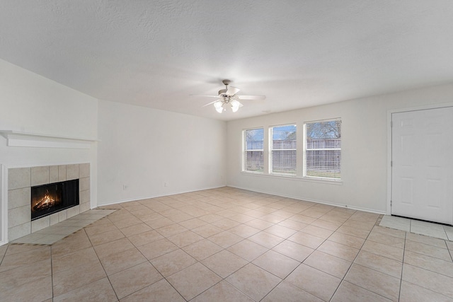 unfurnished living room featuring ceiling fan, a fireplace, a textured ceiling, and light tile patterned floors