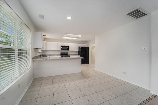 kitchen featuring sink, white cabinetry, kitchen peninsula, light stone countertops, and black appliances