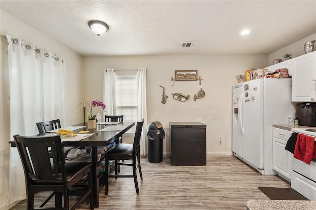 dining room with a textured ceiling and light hardwood / wood-style floors