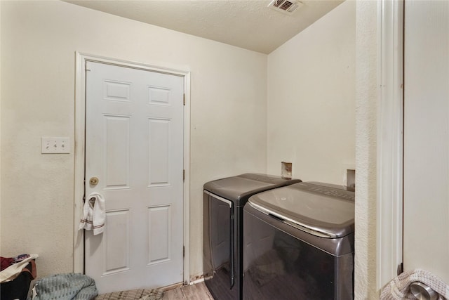 washroom with washer and dryer, a textured ceiling, and wood-type flooring