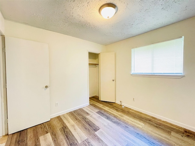 unfurnished bedroom featuring a textured ceiling, light hardwood / wood-style floors, and a closet