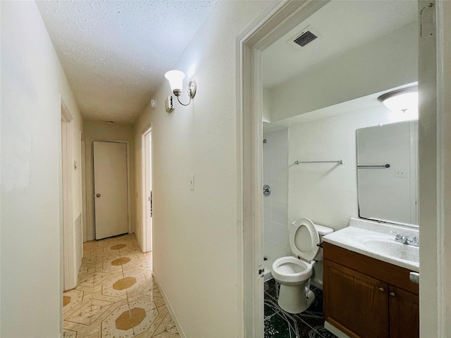 bathroom featuring vanity, a textured ceiling, and toilet