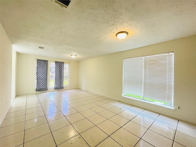 spare room with light tile patterned floors and a textured ceiling