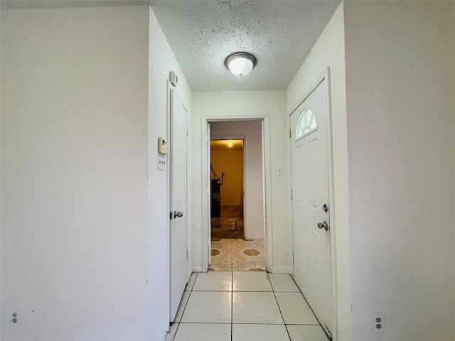 hallway with light tile patterned floors and a textured ceiling