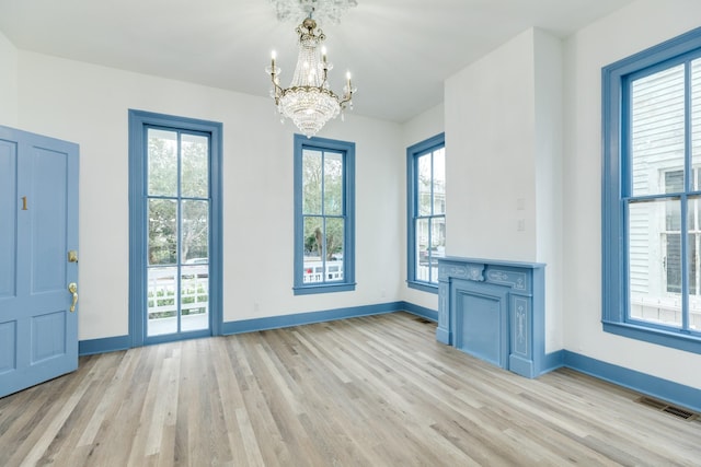 interior space with light hardwood / wood-style flooring, an inviting chandelier, and a healthy amount of sunlight