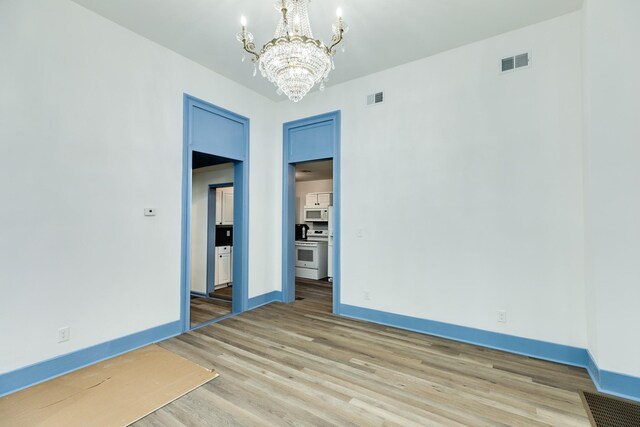 unfurnished room with a chandelier and hardwood / wood-style flooring