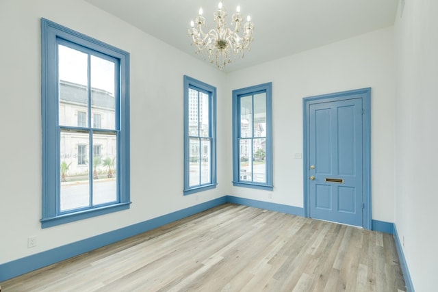 spare room featuring light wood-type flooring and an inviting chandelier