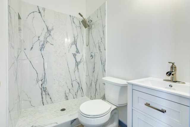 bathroom with tiled shower, vanity, and toilet